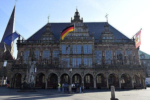 Beflaggtes Rathaus. Rechts, in der Mitte und Links sind jeweils eine Flagge gehisst