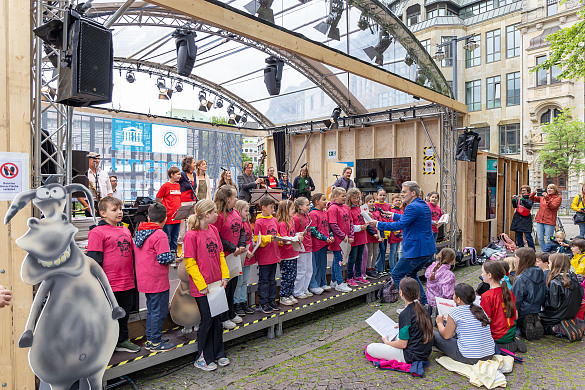 Blick auf die Bühne wo Schülerinnen und Schüler singen.